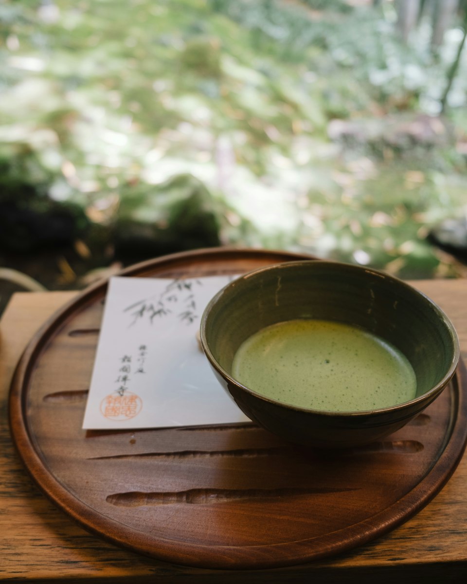 A bowl of ceremonial matcha on a lacquered tray in a bamboo garden