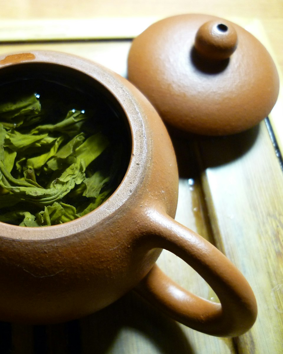 Pan-fired green tea leaves steeping in a clay teapot